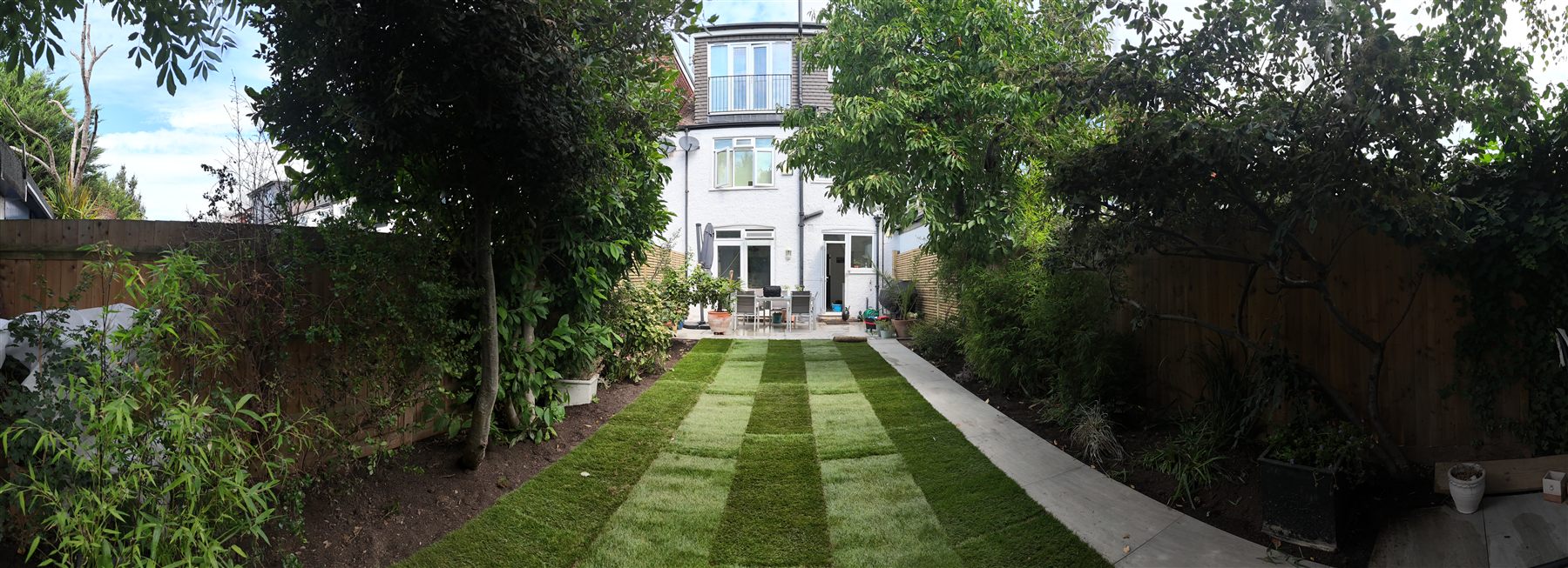 Wide panorama of a full garden transformation with lawn, paving and fencing, Surrey